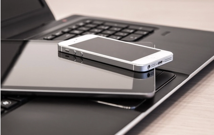 a cell phone laying on top of a tablet next to a laptop