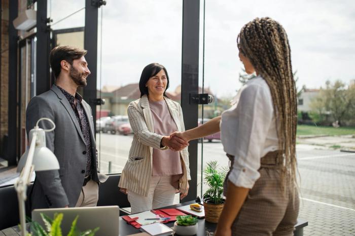 two women shake hands in an office