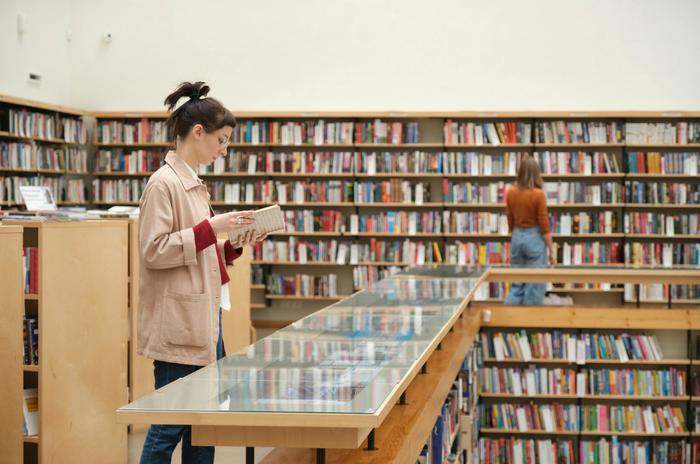 a woman is reading a book in a library .