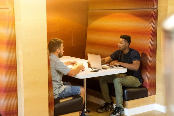 two men are sitting at a table with a laptop .