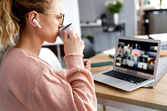 a woman is drinking coffee while sitting in front of a laptop computer .