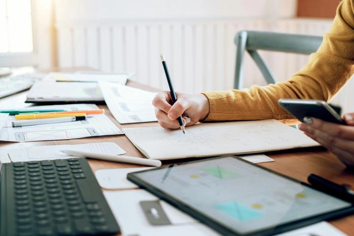 a person is sitting at a table writing on a piece of paper .