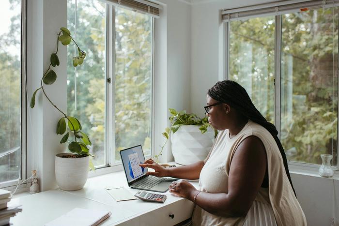 a woman is sitting at a desk using a laptop computer .