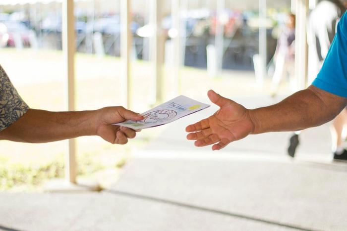 A man is handing a flyer to another man.
