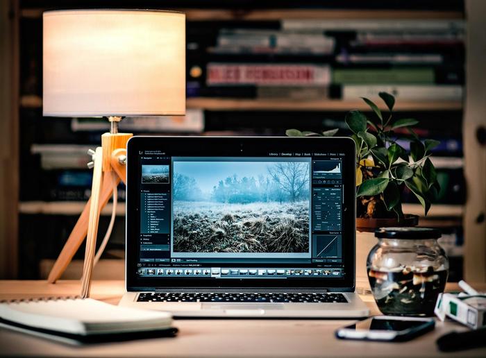 a laptop computer is open to a picture of a field on a desk .