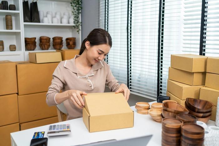a woman is sitting at a desk holding a cardboard box .