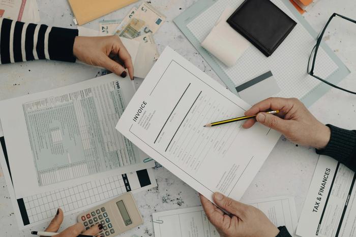 a couple of people are sitting at a table with papers and a calculator .