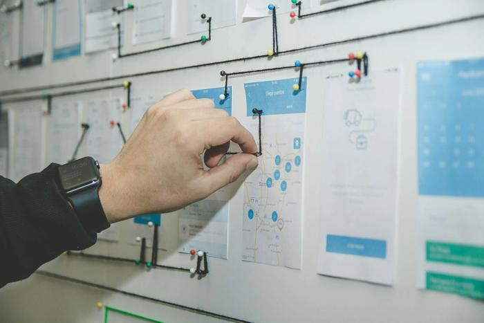 Image is a stock photo showing person mapping customer journey across an interface