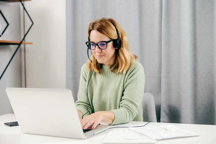 a woman with a headset works at her laptop