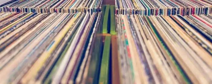 a bunch of records are stacked on top of each other on a shelf .