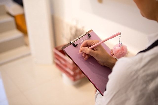 A person writing on a clipboard with a pencil.