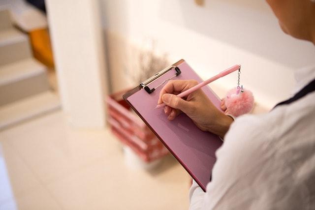 A person writing on a clipboard with a pencil.