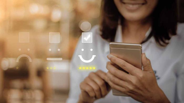 A woman holding a cell phone with a smiley face on it.