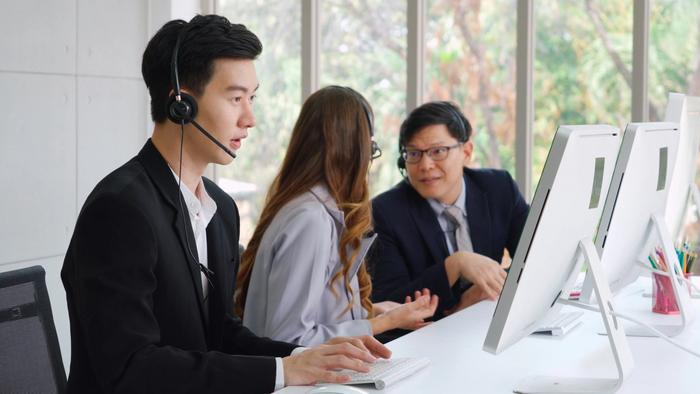 a man wearing a headset is sitting at a desk in front of a computer .