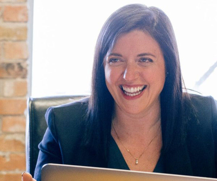 a woman is smiling while holding a laptop
