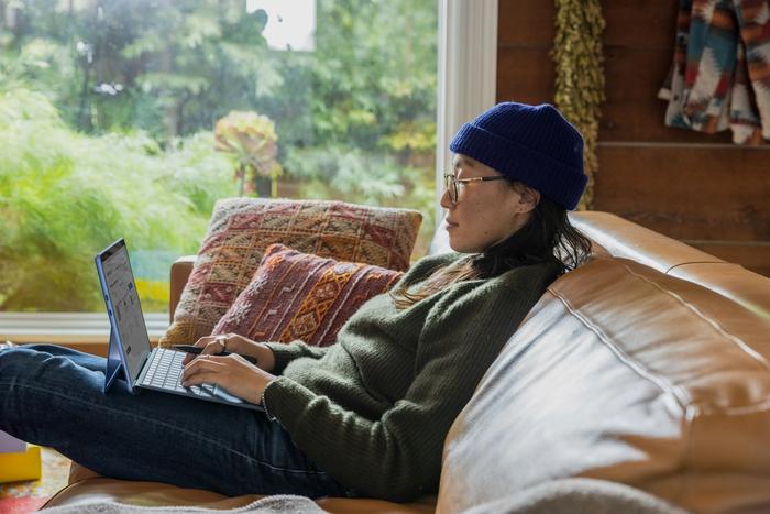 a woman is laying on a couch using a laptop computer.