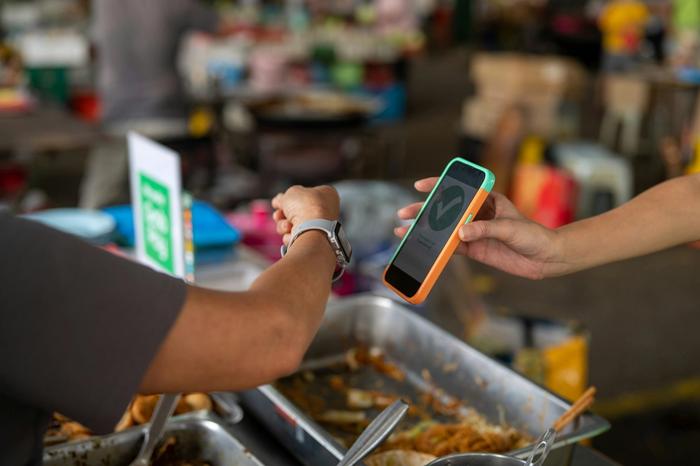 a person is using a smart phone to pay for food .