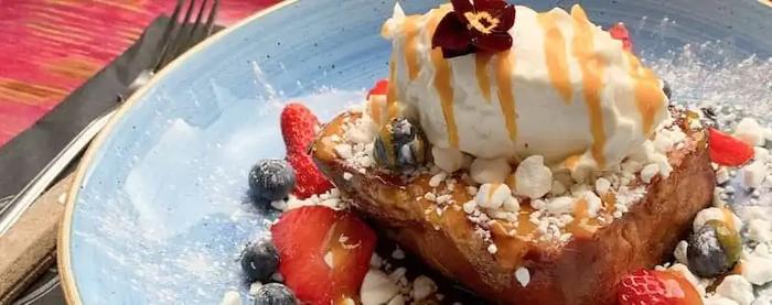 a close up of a plate of food with ice cream and berries on a table .