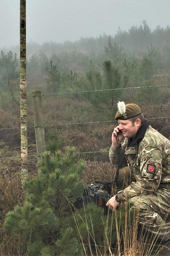 a man in a military uniform is talking on a cell phone