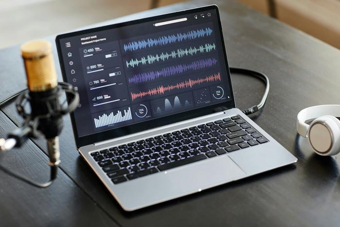 a laptop computer is sitting on a table next to a microphone and headphones .