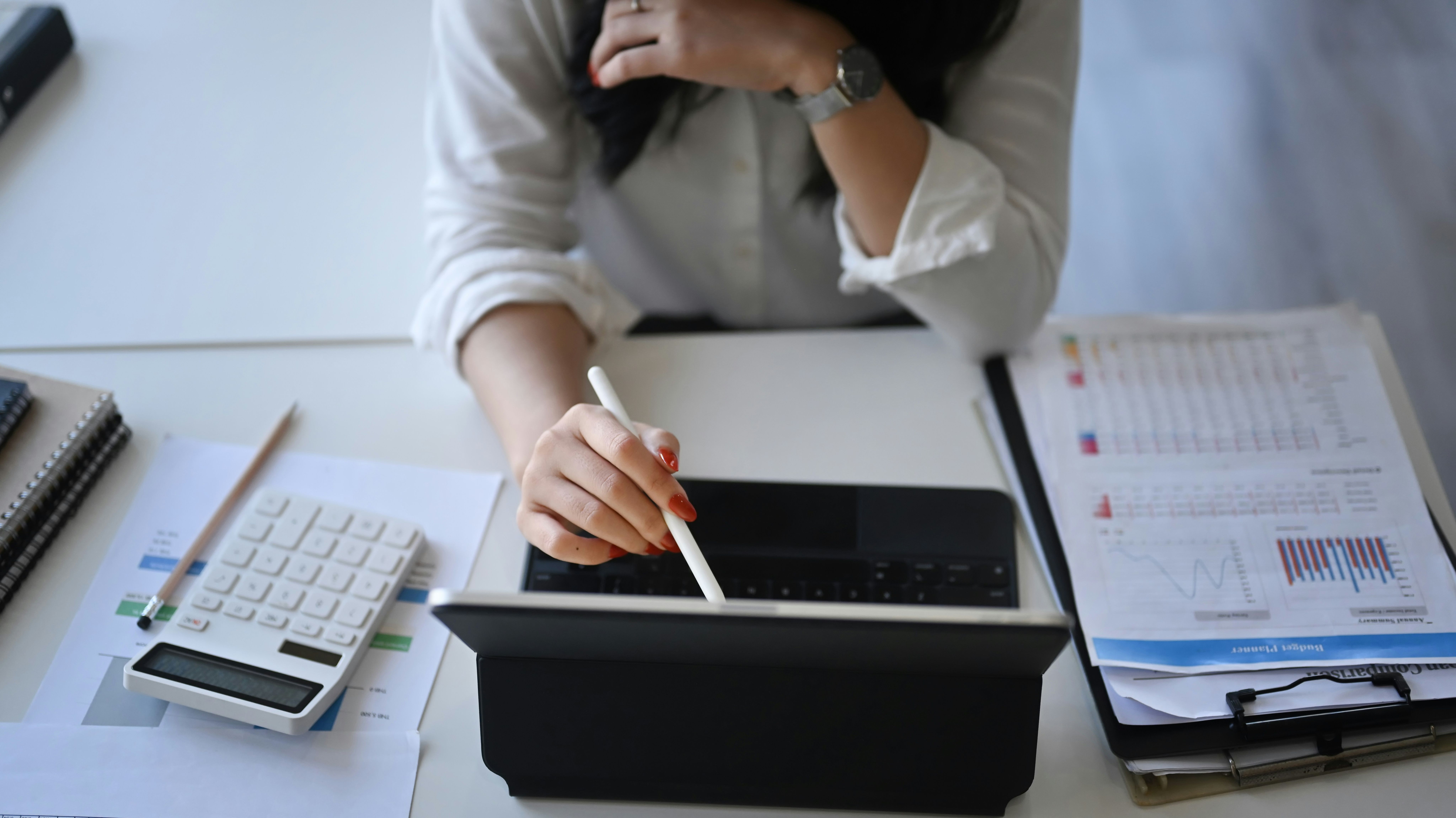 woman sitting at a desk using a tablet computer and a calculator .