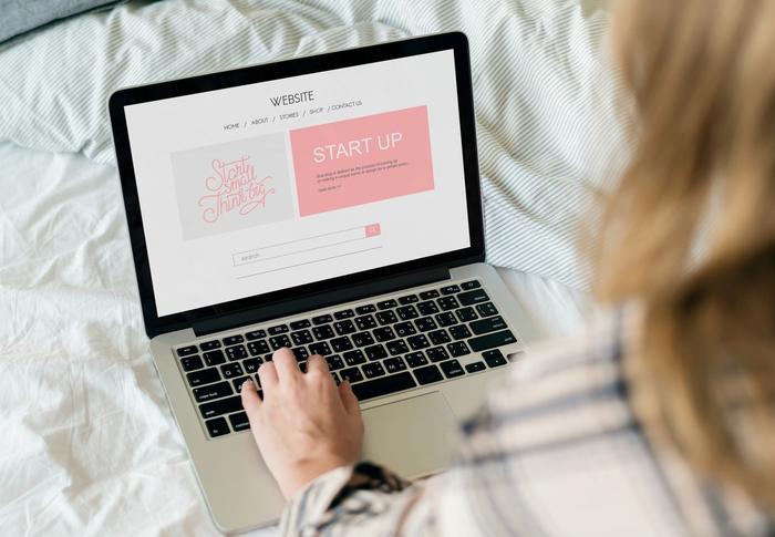 a woman is sitting on a bed using a laptop computer .