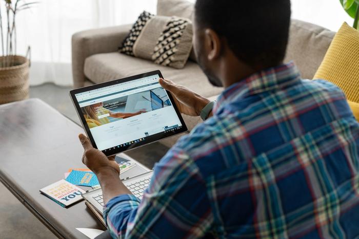 a man is sitting at a table using a tablet computer .