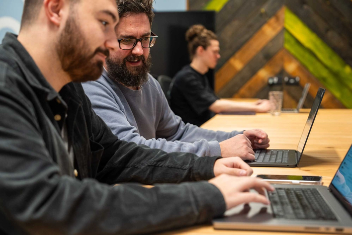 dois homens estão sentados à mesa usando laptops