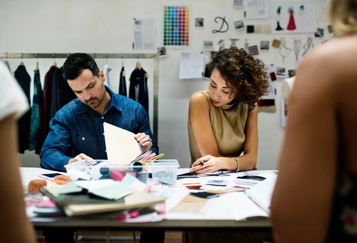 a man and a woman are sitting at a table working on a project .