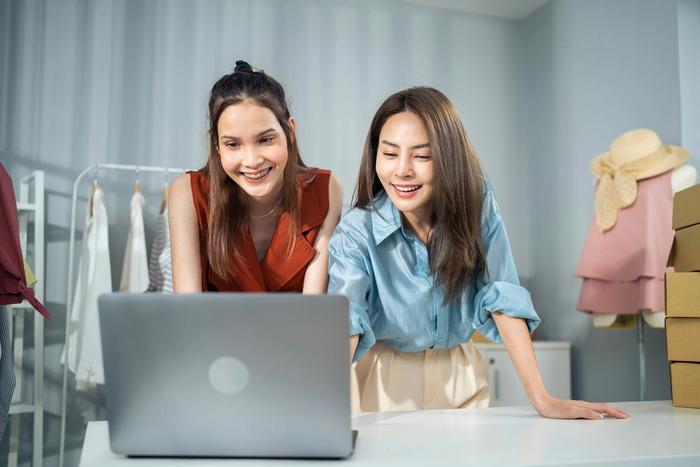 two women are looking at a laptop computer together .