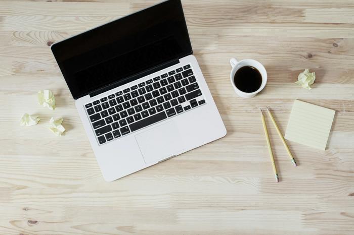 A laptop next to a coffee and post-it notes