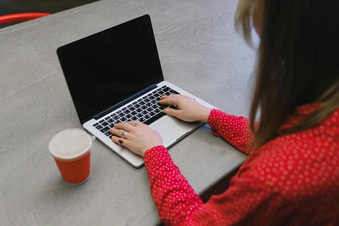 A woman sitting at a table typing on a laptop.