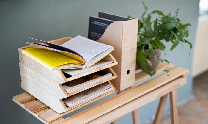 a wooden tray filled with books and magazines is sitting on a wooden table next to a plant .