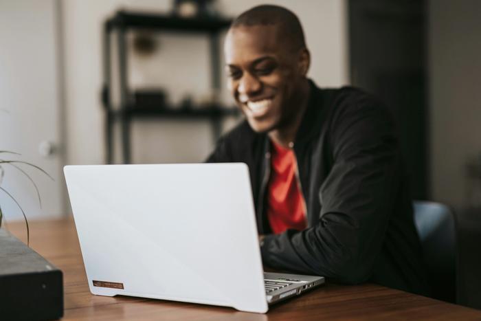 a man is sitting at a table using a laptop computer .