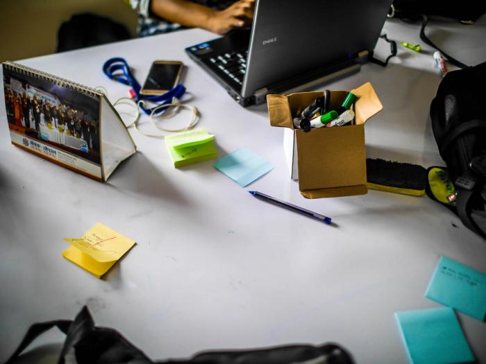 a person is sitting at a table with a laptop and sticky notes on it .