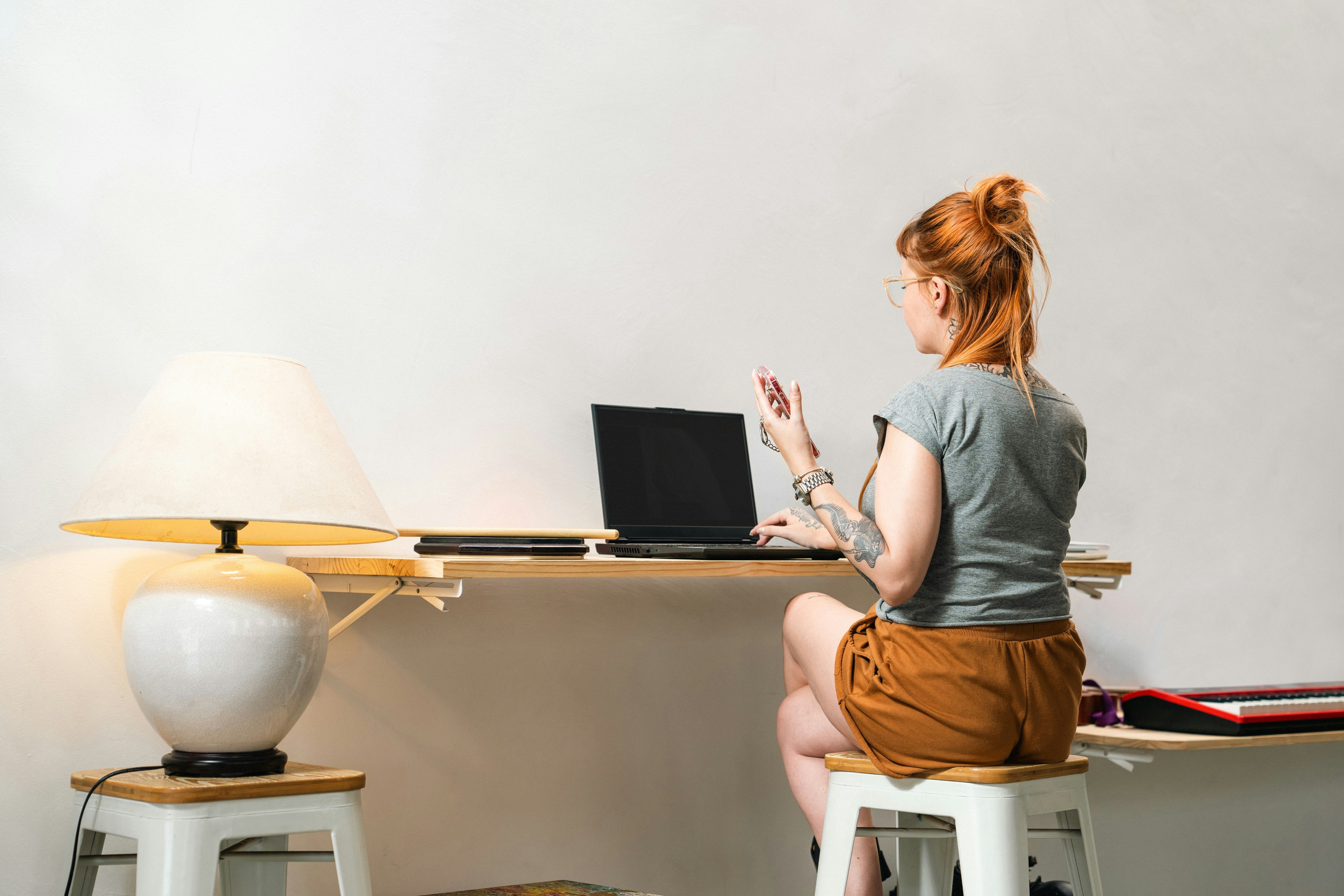 una mujer está sentada en un escritorio usando una computadora portátil .