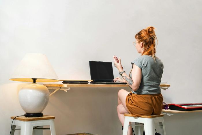 a woman is sitting at a desk using a laptop computer .