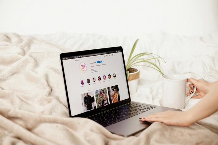 a person is sitting on a bed using a laptop computer .