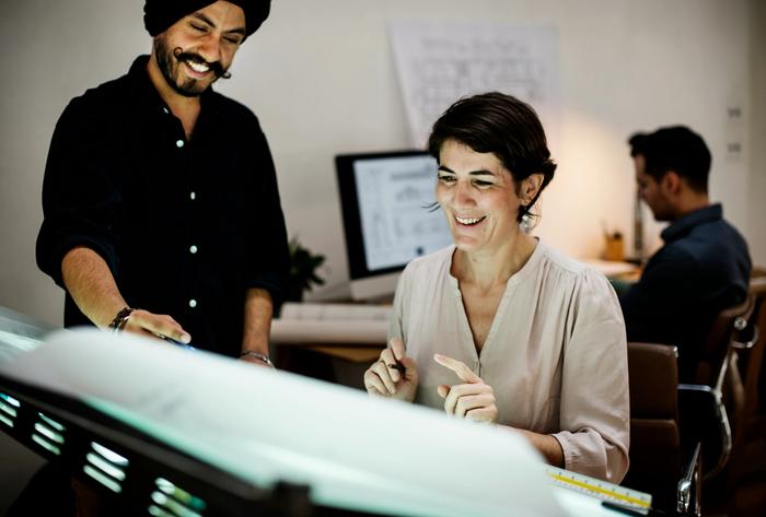 a man and a woman are looking at a computer screen in an office .