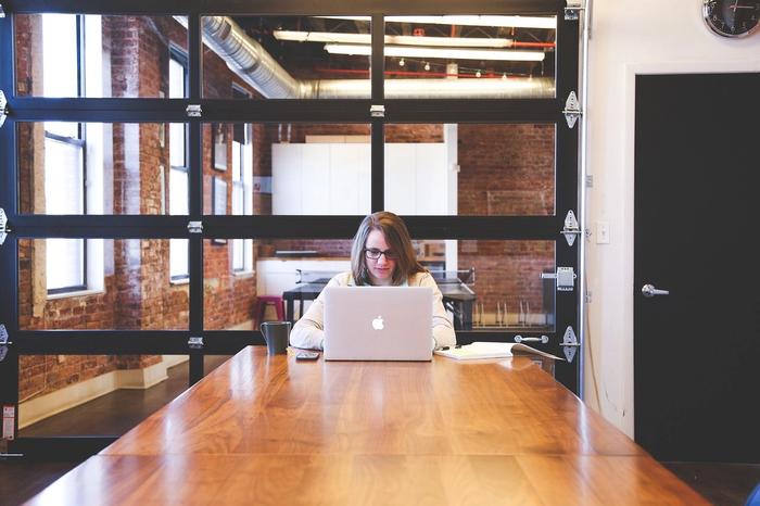 A woman is sitting at a table using a laptop.