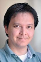 a man in a blue shirt is smiling for the camera .