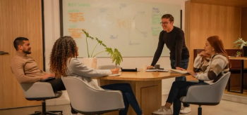 People meeting around a table with a whiteboard