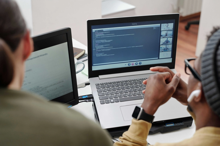 two people are looking at laptop screens