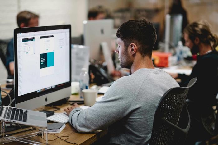 a man is sitting at a desk in front of a computer .