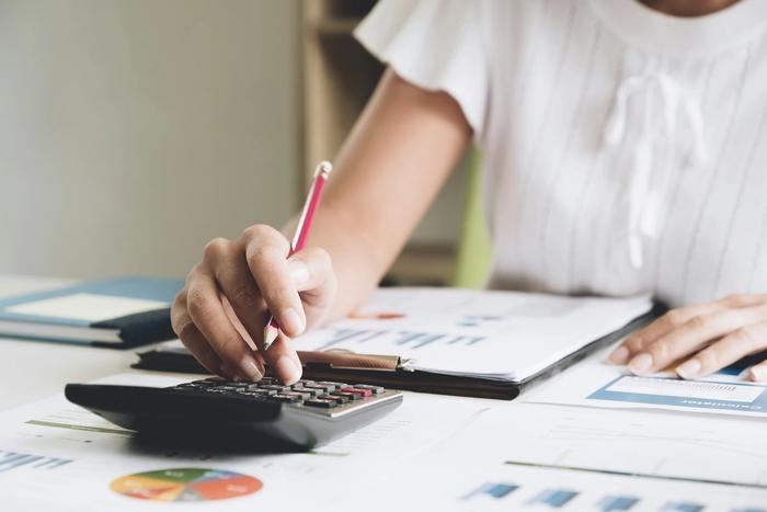 a woman is using a calculator and writing on a piece of paper .