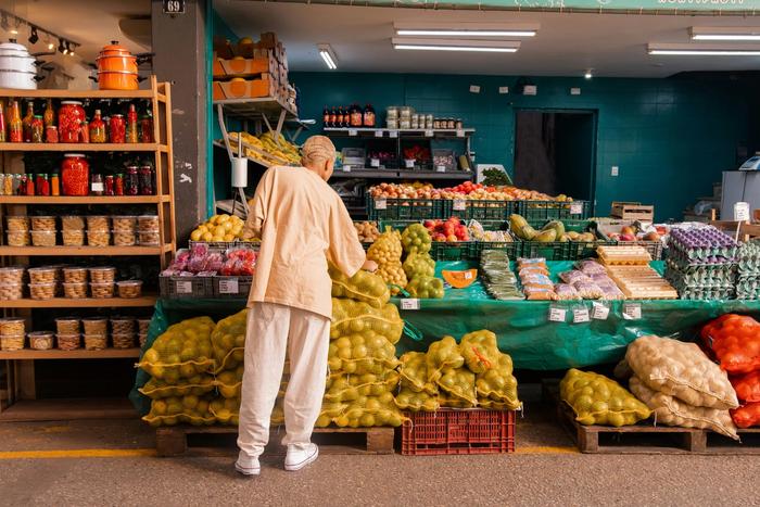 un hombre está parado frente a un puesto de frutas en un mercado.
