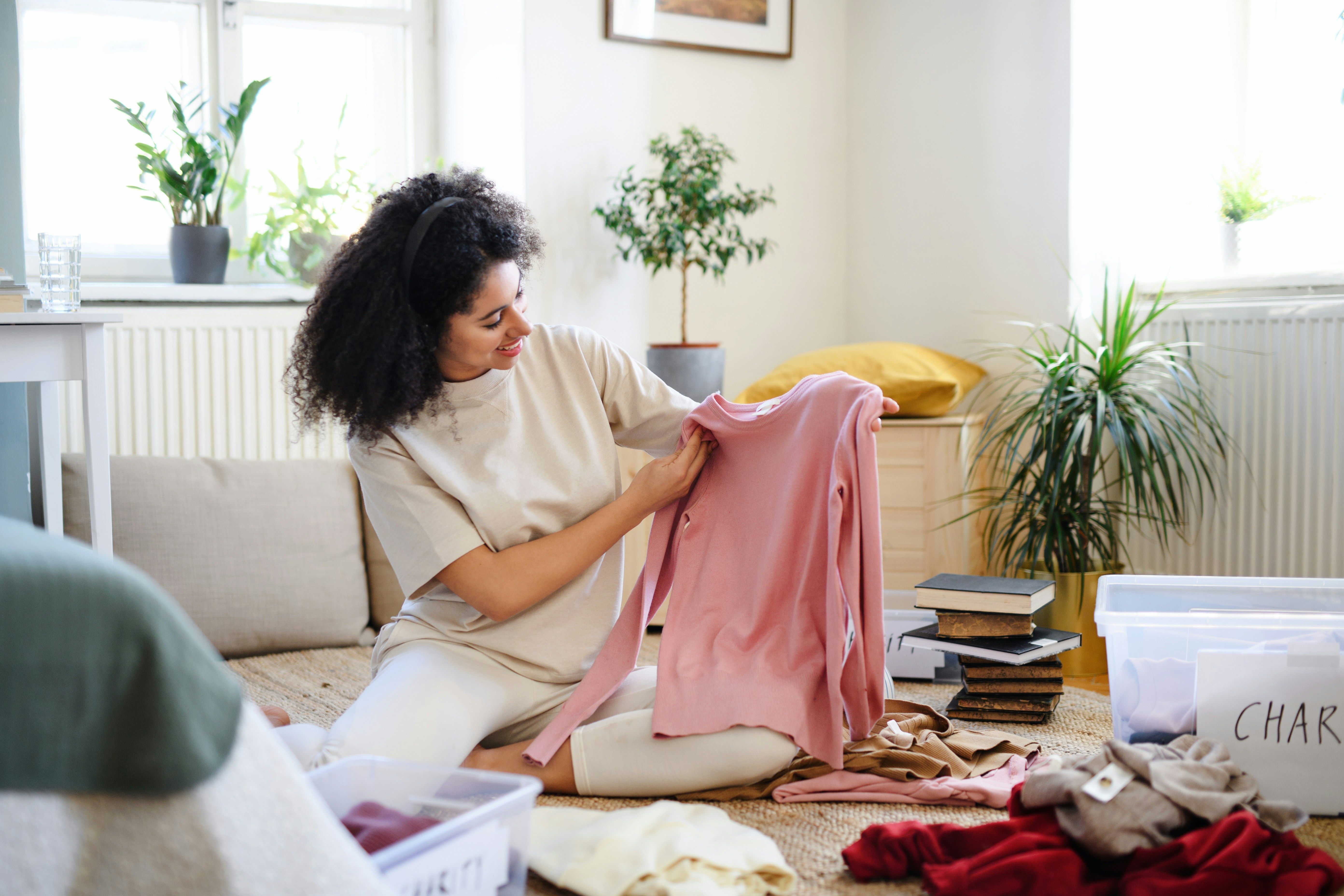a woman is sitting on the floor holding a pink shirt .