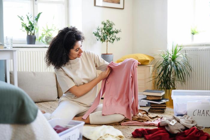a woman is sitting on the floor holding a pink shirt .