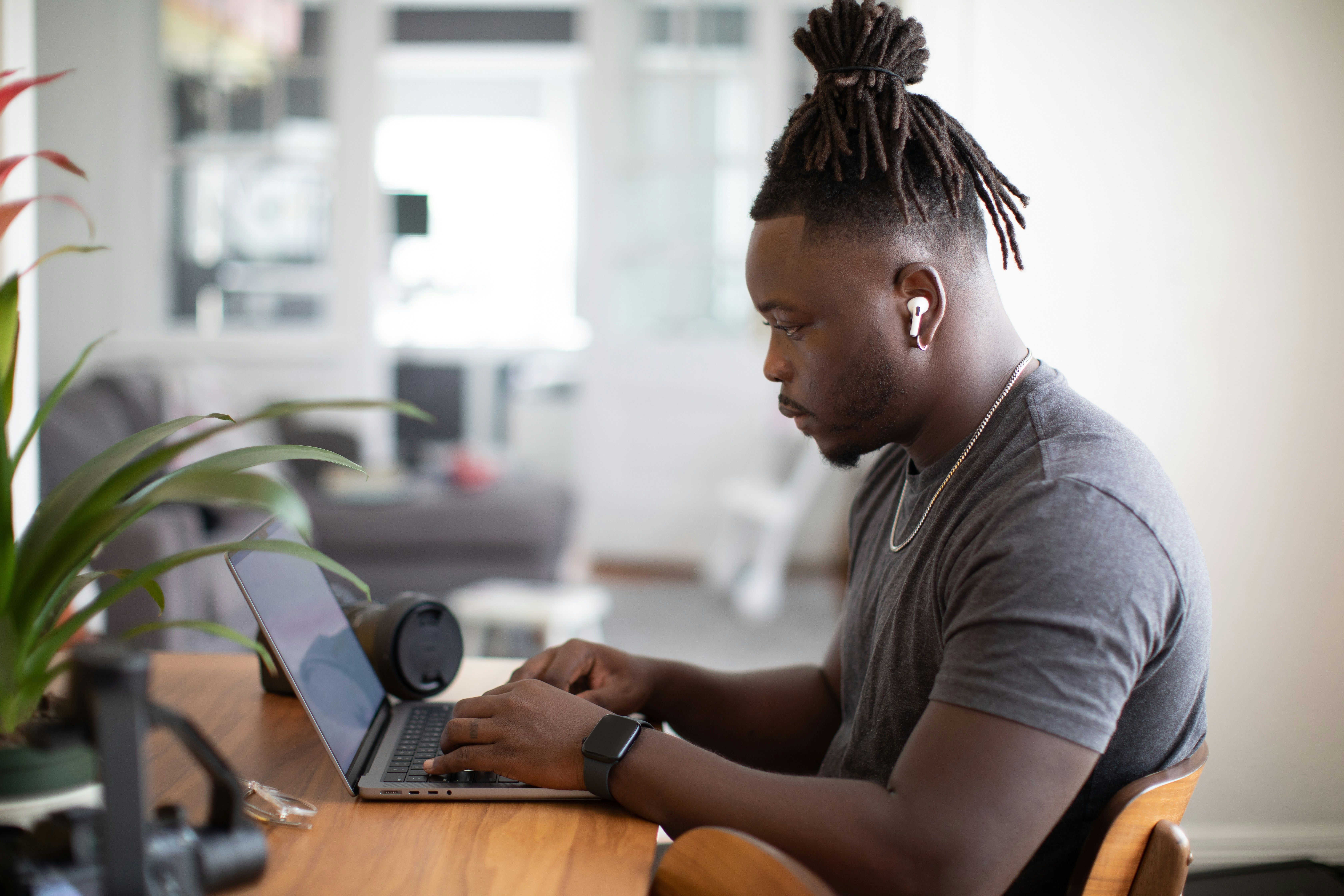 a man is sitting at a table using a laptop computer .