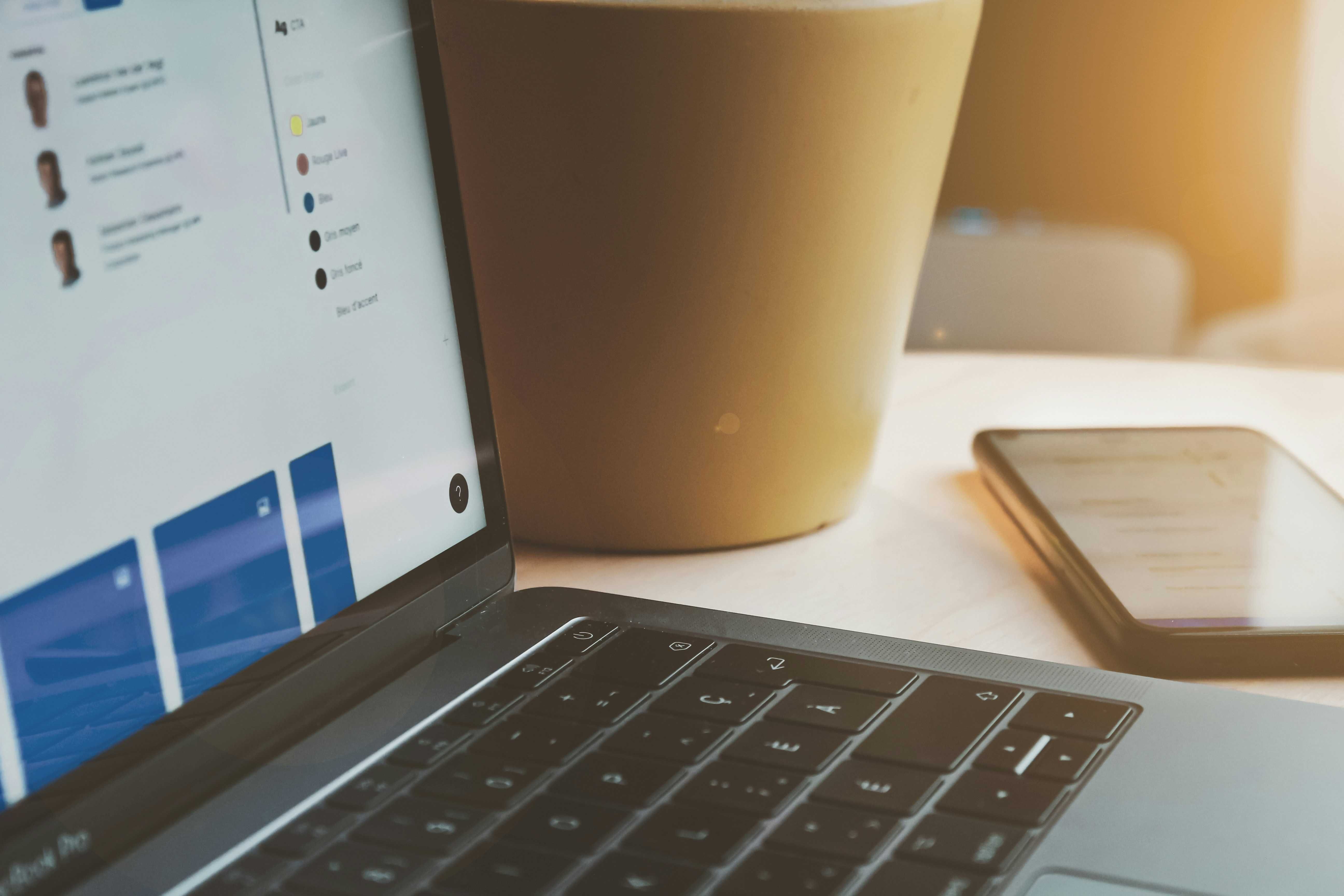 a laptop next to a brown coffee cup